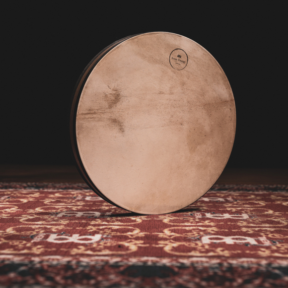 A drum sitting on a rug in a dark room.