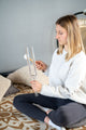 A woman sitting on a bed holding a **Meinl Crystal Tuning Fork 261.63 HZ / C4, 15"** during **meditation**.