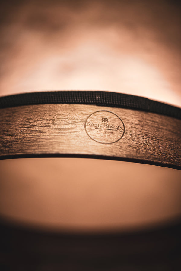 A close up of a Meinl 18" Woven Synthetic Head Hand Drum with a logo on its wooden plate.