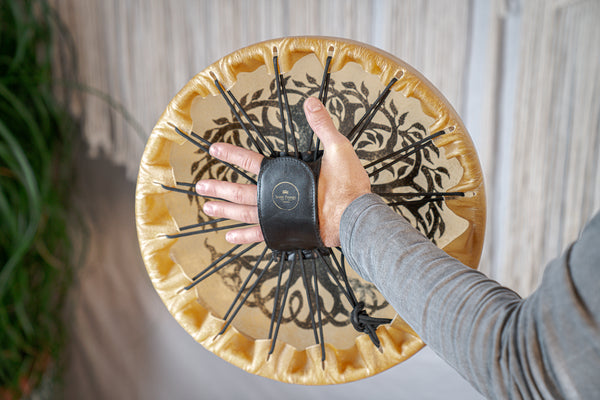 A person's hand is holding a Meinl 15" Native American-Style Hoop Drum, Tree of Life.