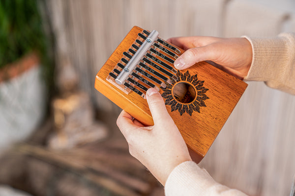 A person engaged in sound healing therapy, holding a Meinl 10 notes Kalimba made of Mahogany.