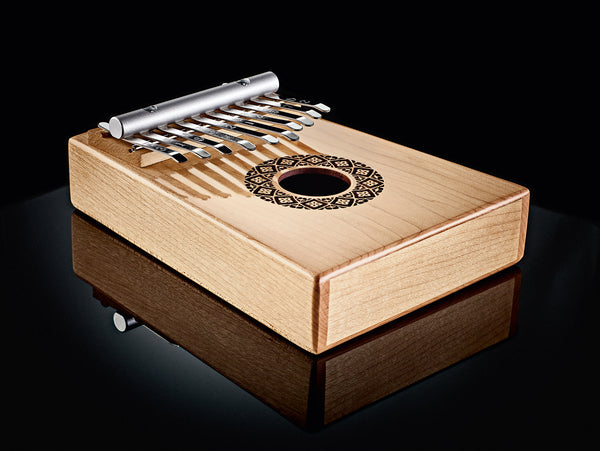 An enchanting Thumb Piano, also known as a Meinl Sonic Energy Soundhole Kalimba, crafted from wood, delicately placed on a sleek black surface. This harmonious instrument holds the power