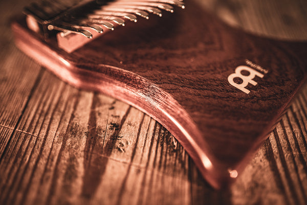 A Meinl 17 notes Kalimba, Sapele, a melodic instrument, resting on a beautiful wooden table.