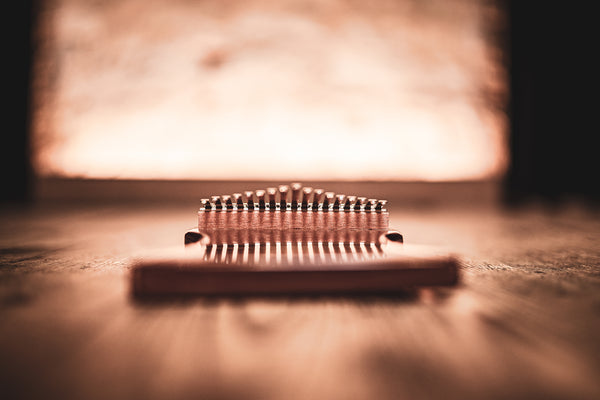 A Meinl 17 notes Kalimba, Sapele, a melodic instrument, sitting on top of a wooden table.