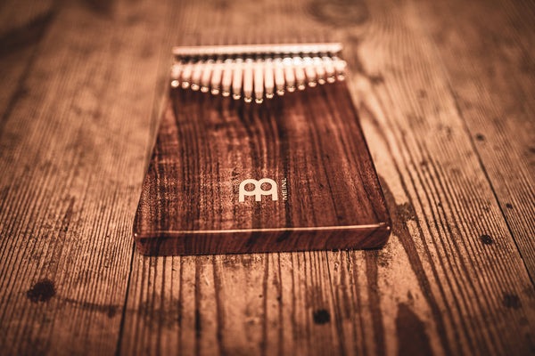 A Meinl 17 notes Kalimba, Acacia sitting on top of a wooden table.