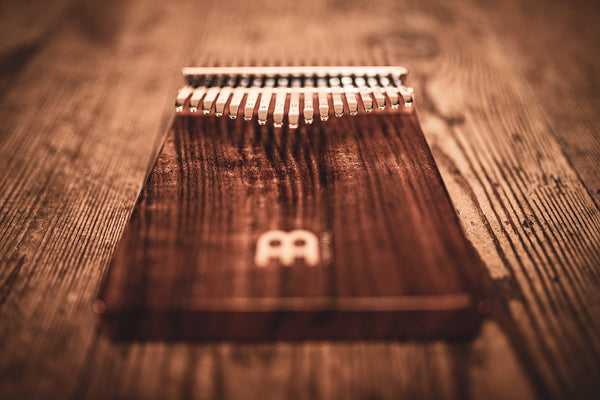A Meinl 17 notes Kalimba, Acacia made of acacia wood is sitting on top of a wooden table.