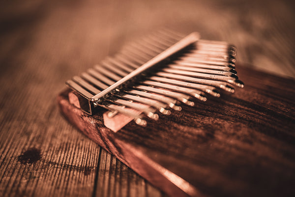 A Meinl 17 notes Kalimba, Acacia, a melodic instrument made of acacia wood, resting on top of a wooden table.