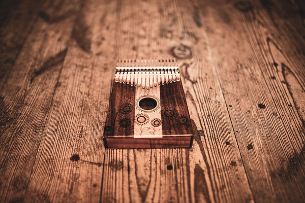 The Meinl 17 notes Kalimba, Maple & Acacia, a melodic instrument, rests on top of a wooden floor.