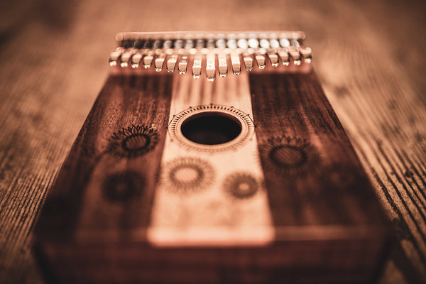 The Meinl 17 notes Kalimba, Maple & Acacia, a melodic instrument in the C Major scale, is placed on top of a wooden table.
