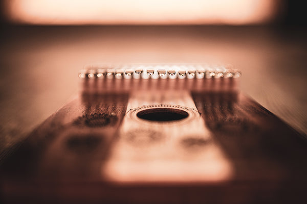 A close up of the Meinl 17 notes Kalimba, Maple & Acacia, a melodic instrument, placed on a wooden table.