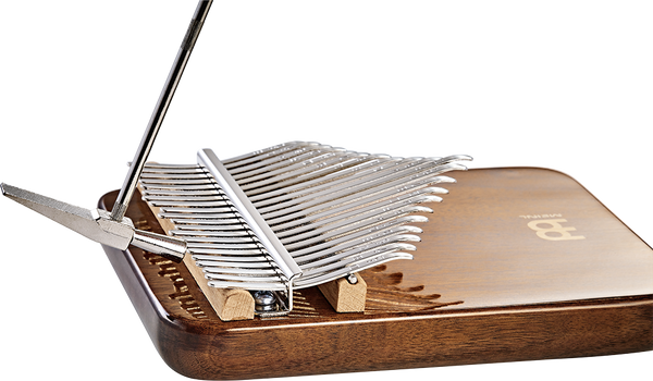A melodic instrument made of black walnut wood, resembling a Meinl 21 notes Kalimba, with a pair of scissors on it.