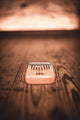 A Meinl 8 notes Kalimba, Maple, made of maple wood, resembling a shaver, resting on top of a wooden floor.