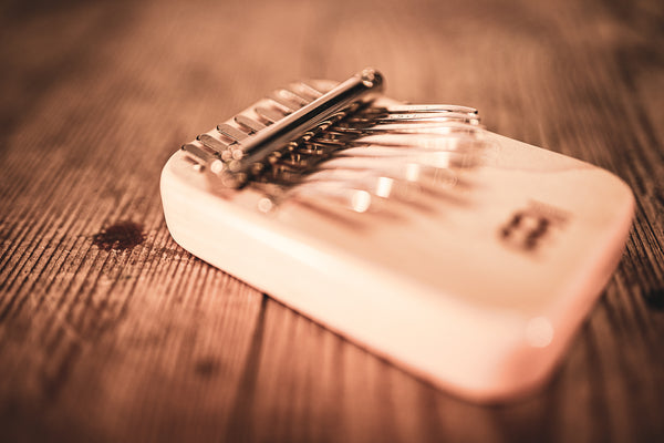 A melodic instrument made of maple wood, known as a Meinl 8 notes Kalimba, sitting on top of a wooden table.