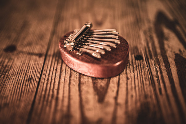 A melodic instrument, specifically an 8 notes Kalimba, sitting on top of a wooden table made from sapele wood (Meinl).