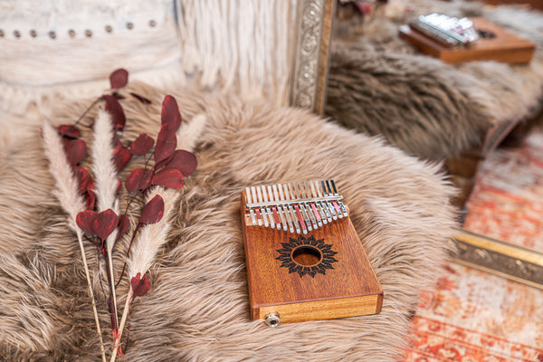 A Meinl Mahogany Kalimba with 17 notes sits on top of a fur rug.