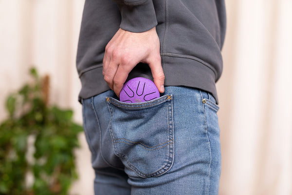 A man in jeans with a Meinl 3" Tongue Drum, A Major, Lotus Flower, Purple in his pocket.
