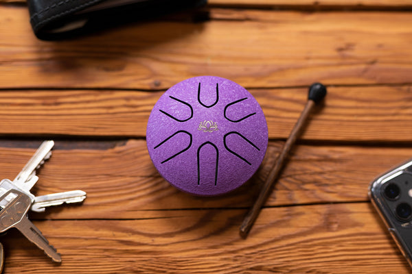 A purple Meinl speaker sits on a wooden table next to a phone and keys.