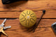 A yellow ball sitting on a wooden table next to a pair of keys, while a 3" Tongue Drum from Meinl Sonic Energy is being played by a sound therapist.